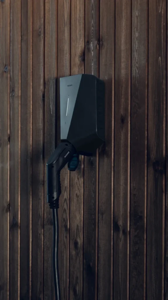 Detail van een Easee laadstation met aangesloten laadkabel op een houten gevel